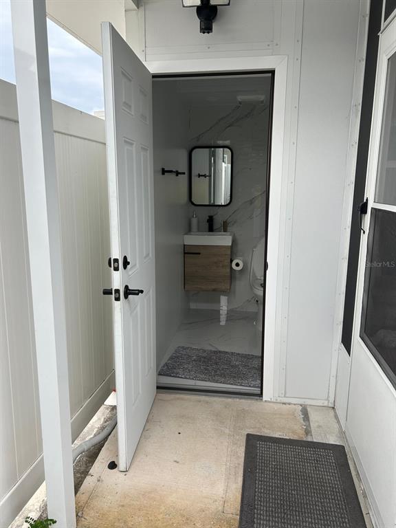 A white door opens to a small bathroom featuring marble-look walls and a floating vanity — 6503 DOVEWOOD PLACE, TAMPA, FL