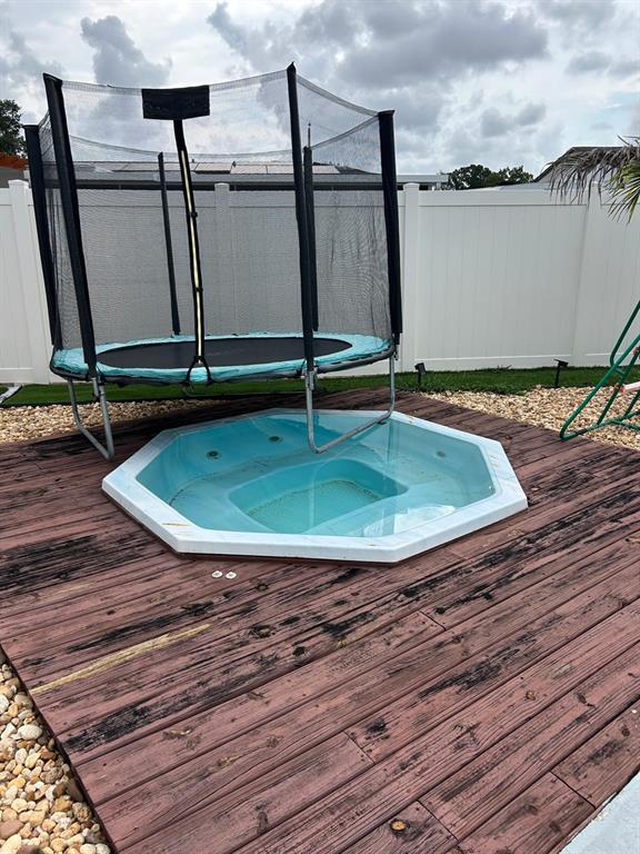 A small trampoline sits directly over an octagonal hot tub on a wooden deck — 6503 DOVEWOOD PLACE, TAMPA, FL