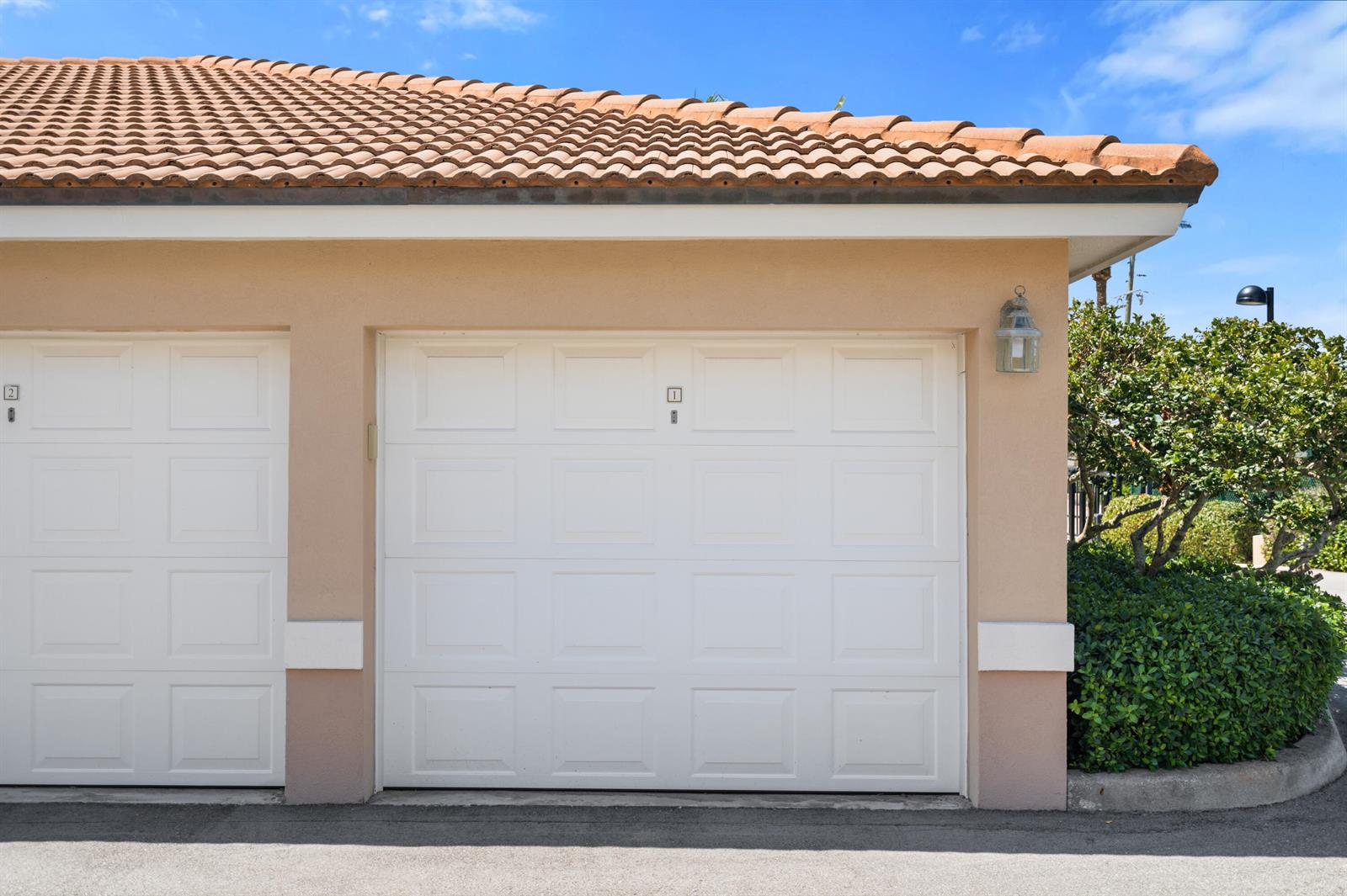 A beige exterior wall features two white garage doors with a lantern light fixture — 2900 N Highway # b, Fort Pierce FL 34949, FORT PIERCE, FL