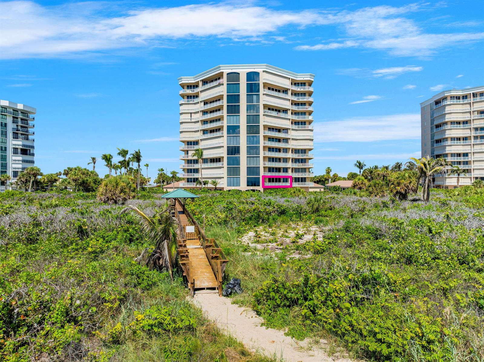 A multi-story residential building stands behind a wooden boardwalk leading through coastal vegetation — 2900 N Highway # b, Fort Pierce FL 34949, FORT PIERCE, FL
