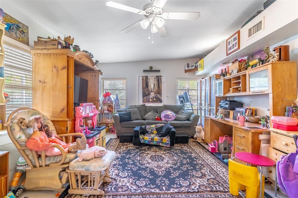 A cluttered living room features a ceiling fan, a large area rug, and wooden furniture — 743 ALFRED DRIVE, ORLANDO, FL