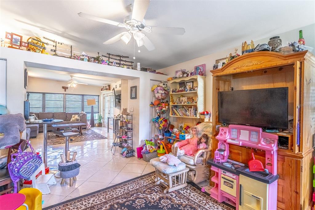 A living room with tile floors, a ceiling fan, and a large wooden entertainment center — 743 ALFRED DRIVE, ORLANDO, FL