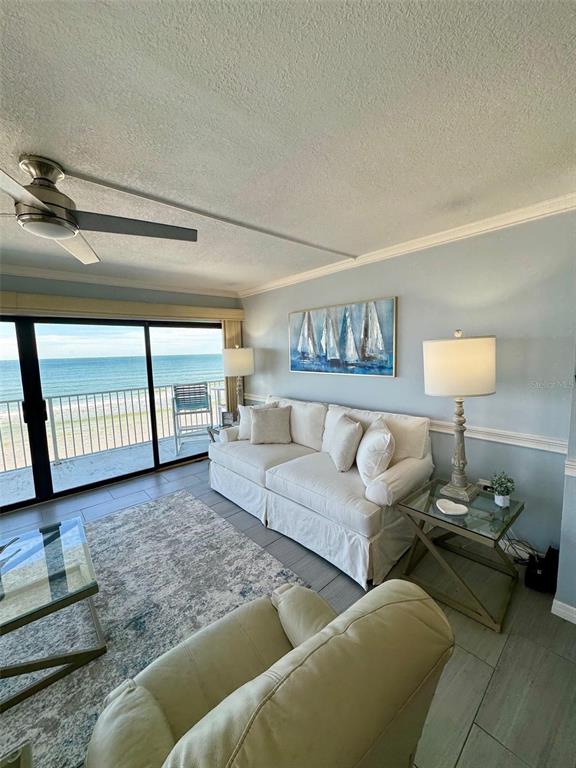 A living room with a white sofa, a glass coffee table, and a balcony overlooking the ocean — 1571 S ATLANTIC AVENUE UNIT 410, NEW SMYRNA BEACH, FL