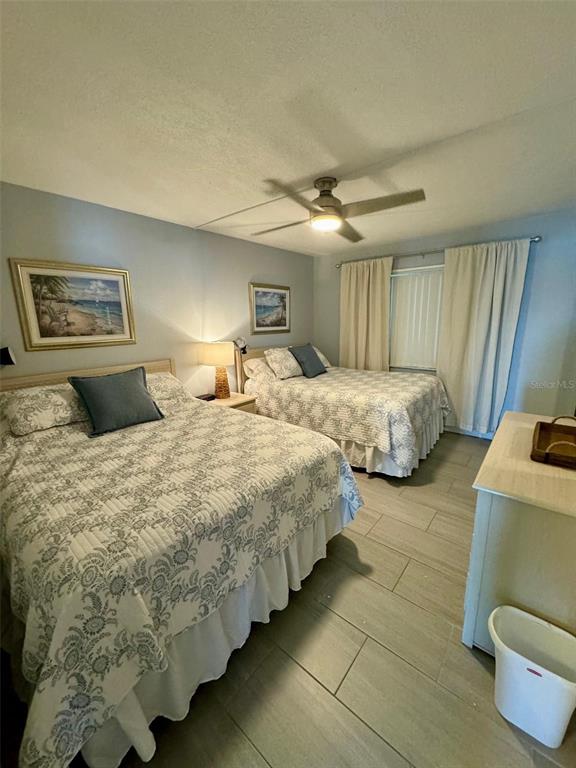 A bedroom features two beds with patterned quilts, tile flooring, and a ceiling fan — 1571 S ATLANTIC AVENUE UNIT 410, NEW SMYRNA BEACH, FL