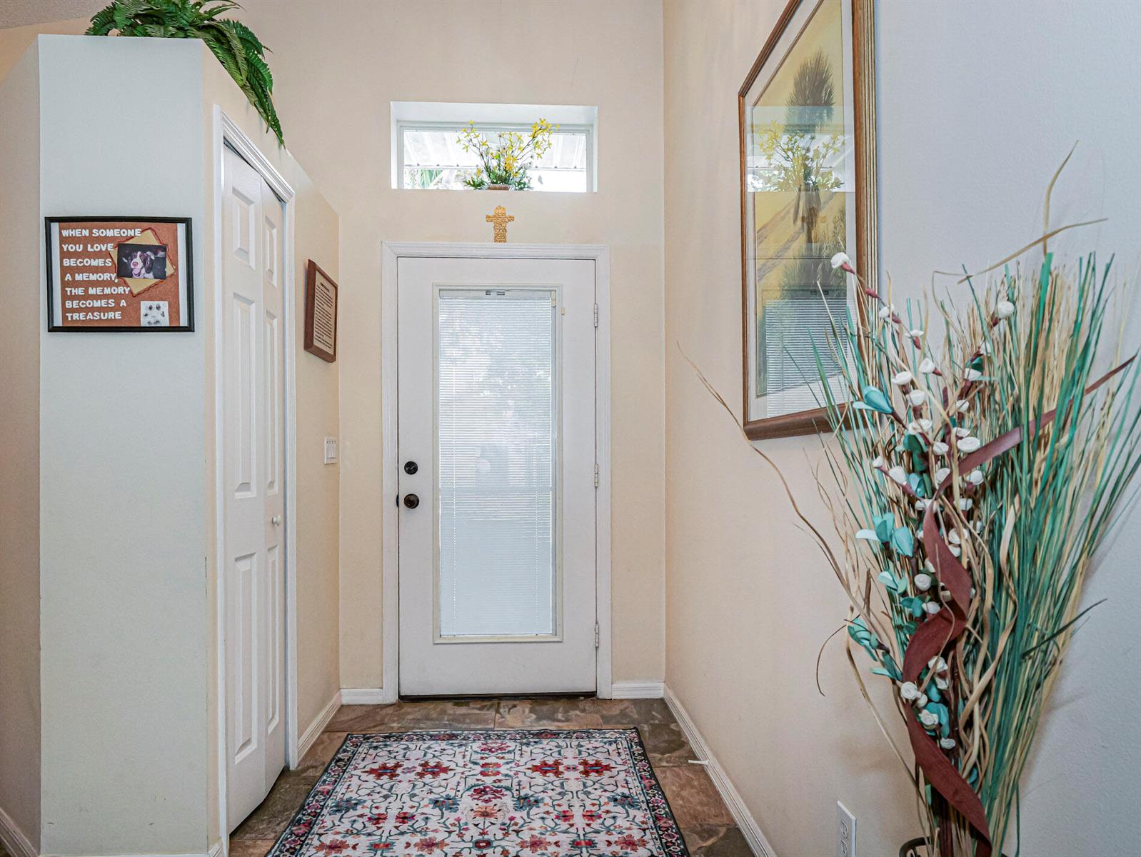 An entryway features a white front door with a transom window, tile flooring, and decor — 1360 10th Manor, Vero Beach FL 32960, VERO BEACH, FL