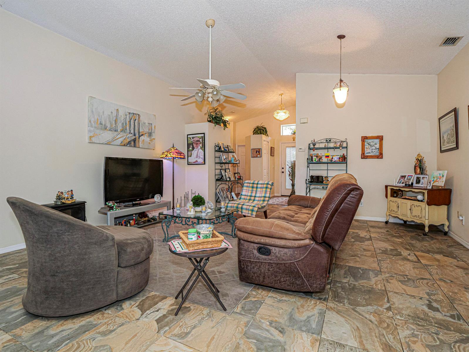 A living room features tile flooring, a brown recliner, a television, and a ceiling fan — 1360 10th Manor, Vero Beach FL 32960, VERO BEACH, FL