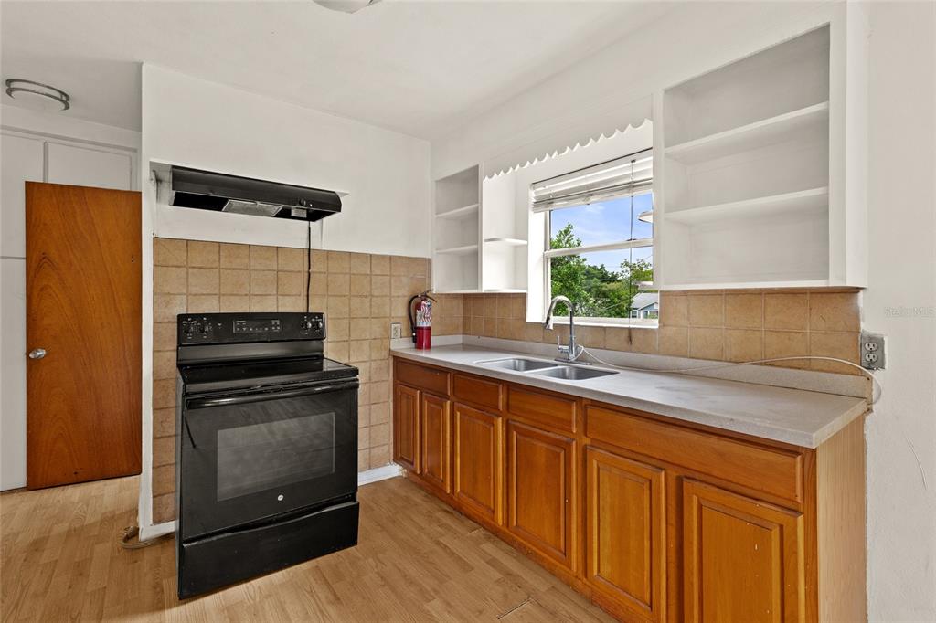A kitchen features wood cabinets, a black stove, a double sink, and tan tile backsplash — 4222 18TH STREET N, ST PETERSBURG, FL