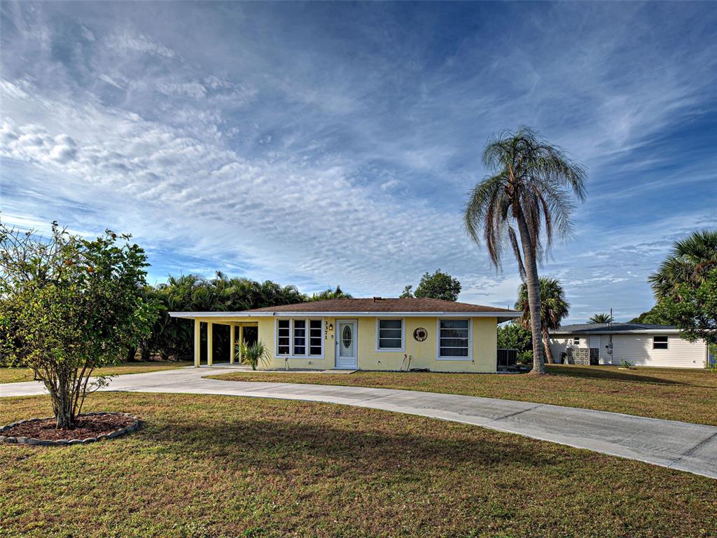A yellow single-story house with a carport and a palm tree in the front yard — 3371 PINETREE STREET, PORT CHARLOTTE, FL