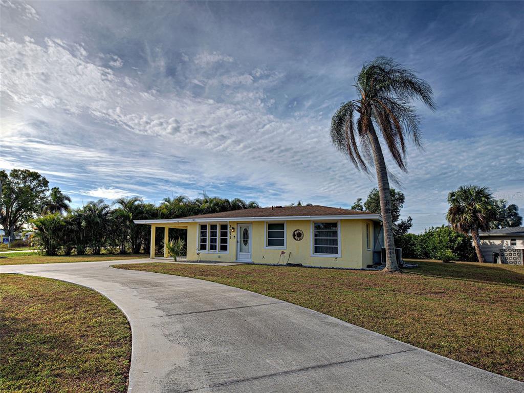 A single-story yellow house with a concrete driveway and a tall palm tree — 3371 PINETREE STREET, PORT CHARLOTTE, FL