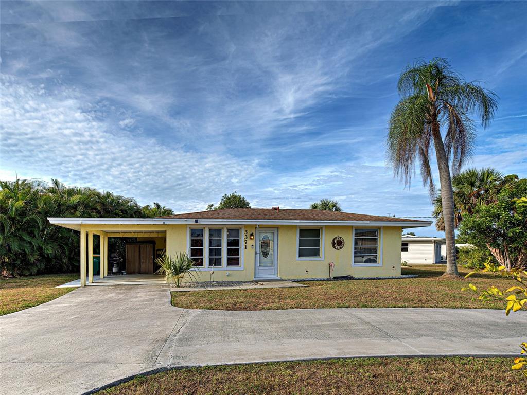 A yellow single-story house with a carport and a palm tree in the front yard — 3371 PINETREE STREET, PORT CHARLOTTE, FL