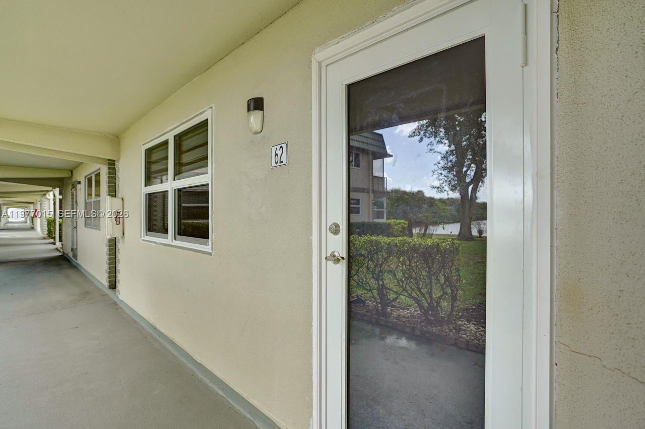 A view of an exterior walkway leading to a residential door marked with number 62 — 62 Monaco B # 62, Delray Beach FL 33446, DELRAY BEACH, FL