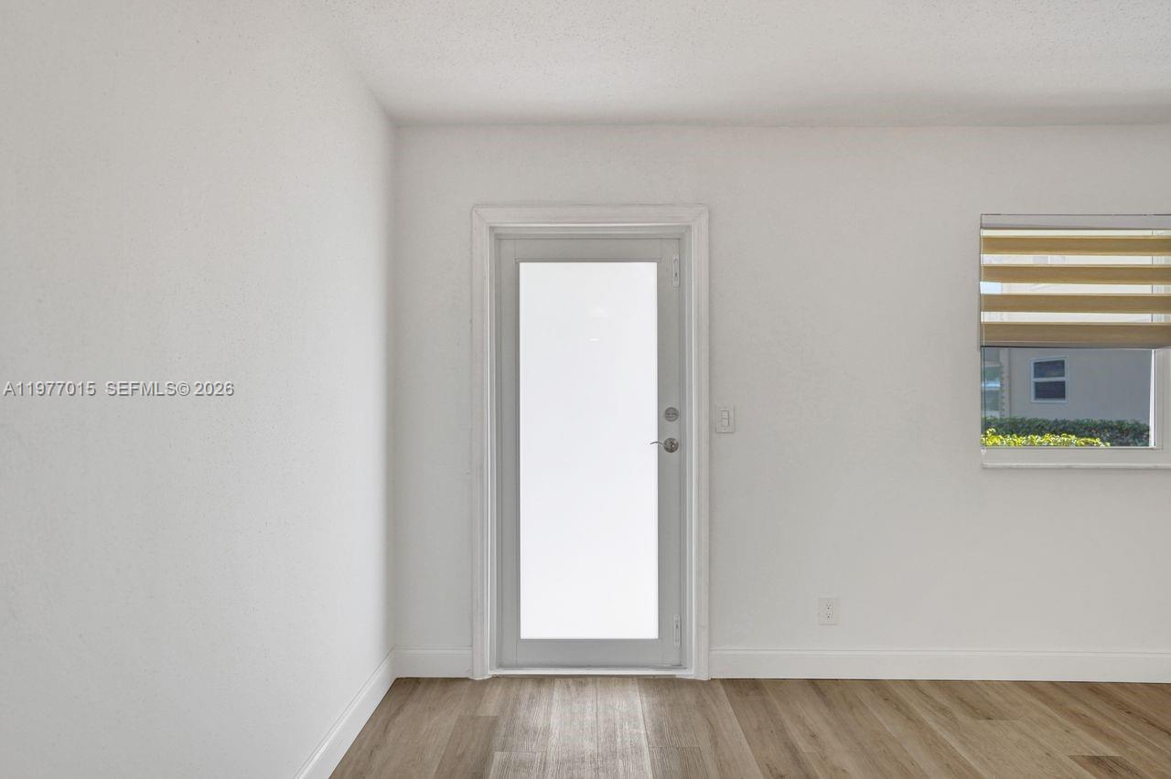 A room with white walls, light wood-look flooring, a glass door, and a window — 62 Monaco B # 62, Delray Beach FL 33446, DELRAY BEACH, FL