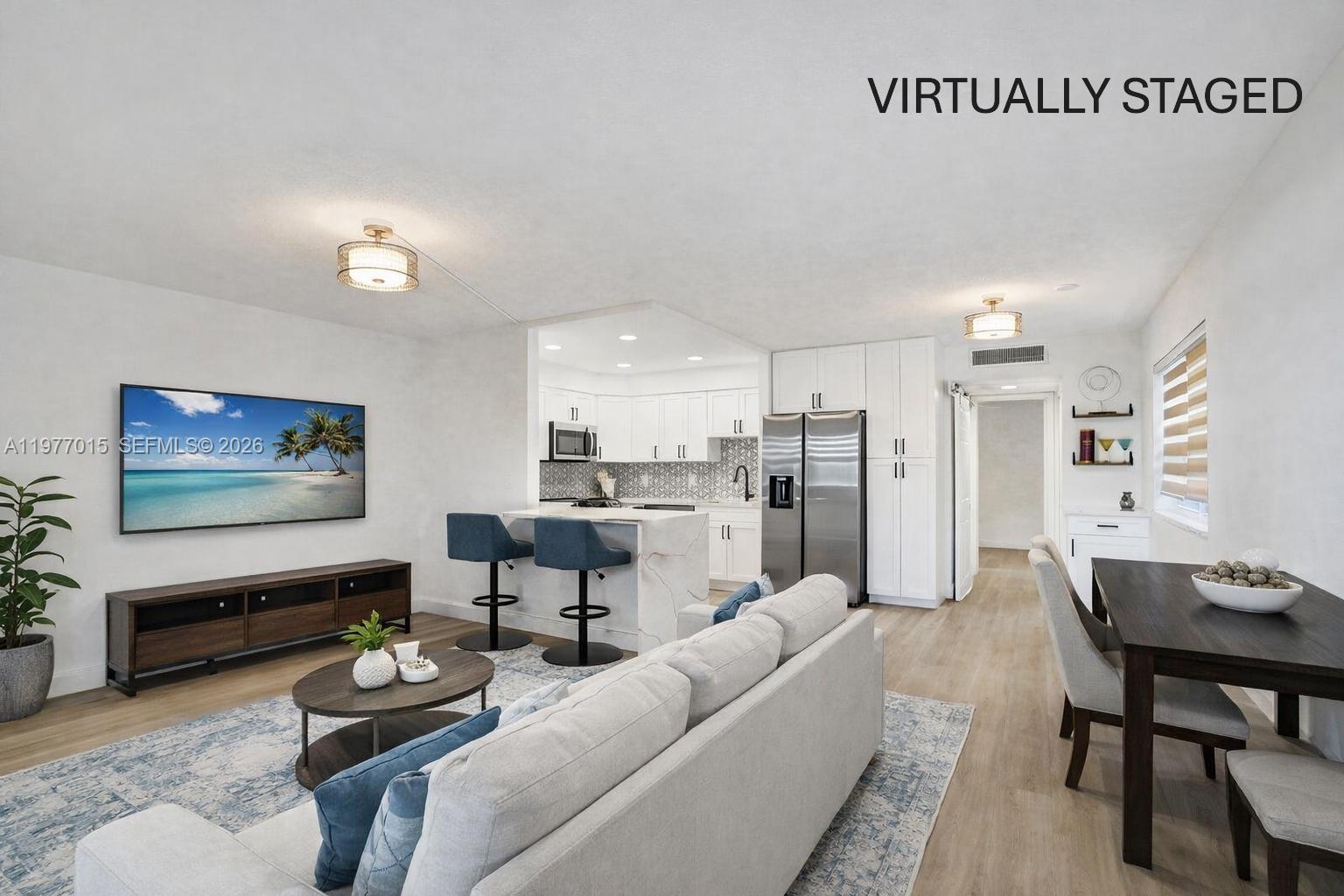 This open-concept living and dining area features a kitchen with white cabinets and stainless appliances — 62 Monaco B # 62, Delray Beach FL 33446, DELRAY BEACH, FL