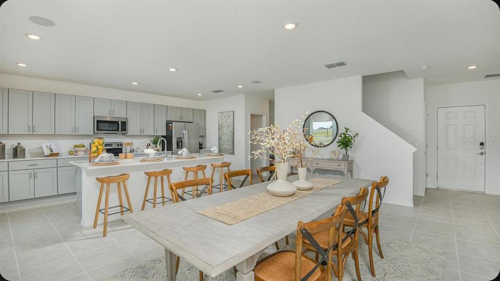 A modern open-concept kitchen and dining area featuring light gray cabinetry and tile flooring — 6769 EQUINOX LANE, NORTH FORT MYERS, FL
