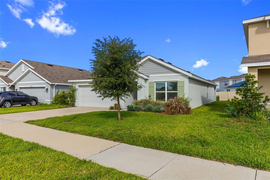 A single-story suburban house with a gray exterior, a two-car garage, and a front lawn — 37207 SHARKS EYE LANE, ZEPHYRHILLS, FL