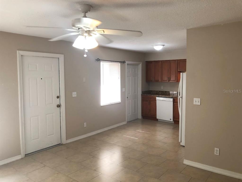 A kitchen with wood cabinets and tile flooring opens into a living area with a ceiling fan — 1419 DAVIDSON STREET, ORLANDO, FL