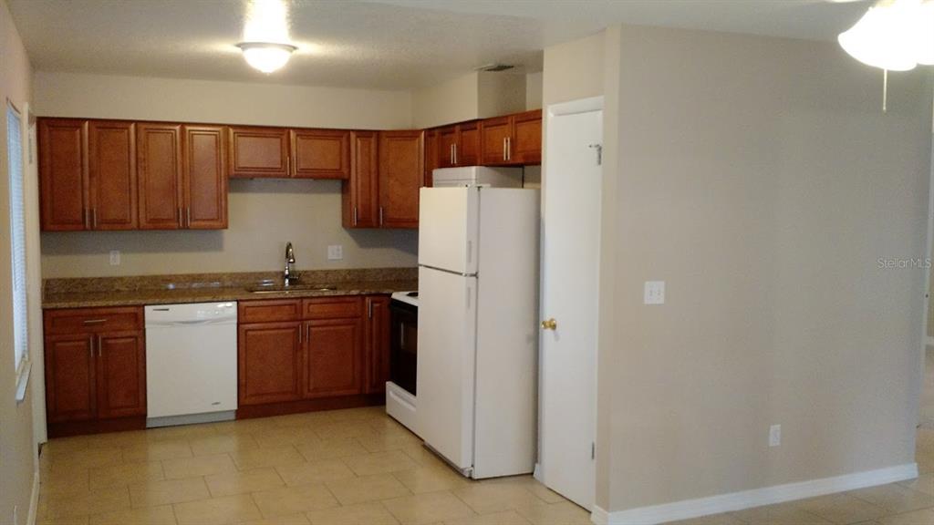 A kitchen features wood cabinets, granite countertops, a white refrigerator, and a white dishwasher — 1419 DAVIDSON STREET, ORLANDO, FL