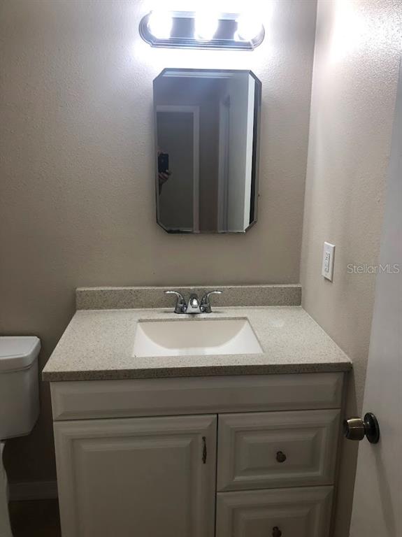 A bathroom vanity with a white cabinet, speckled countertop, sink, and wall-mounted mirror — 1419 DAVIDSON STREET, ORLANDO, FL