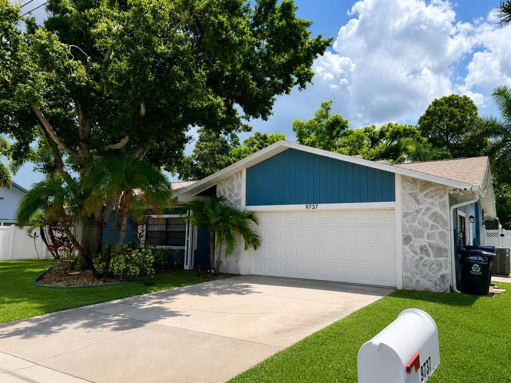 A single-story house with a white garage door, stone siding, and a blue gable — 9737 135TH STREET, SEMINOLE, FL