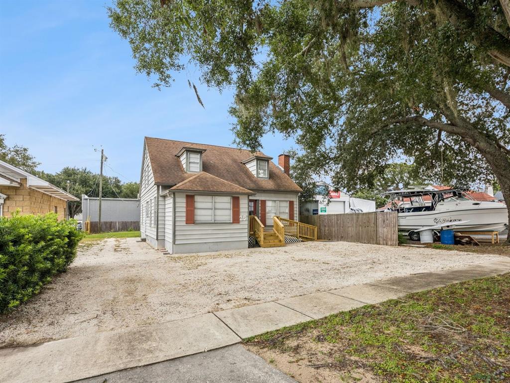 A two-story house with a gravel driveway, wooden front steps, and a boat parked nearby — 25 E PINECREST AVENUE, EUSTIS, FL