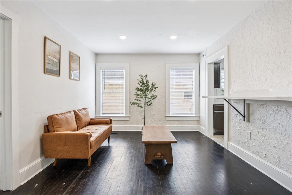 A living room features dark hardwood floors, a tan leather sofa, and a wall-mounted counter — 25 E PINECREST AVENUE, EUSTIS, FL