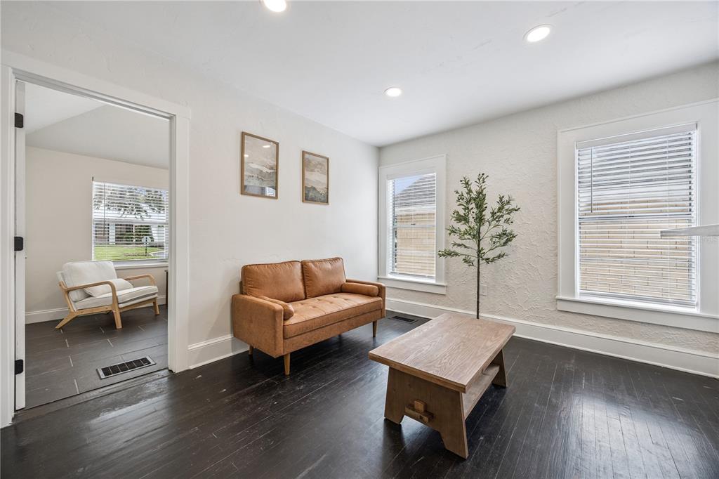 A living room features dark wood floors, a tan leather sofa, and a wooden coffee table — 25 E PINECREST AVENUE, EUSTIS, FL