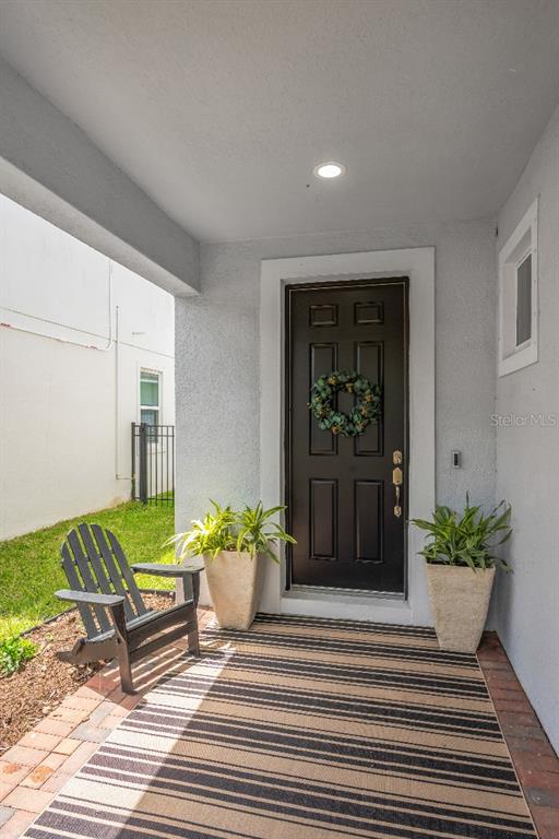 A black front door with a wreath sits on a porch with a striped rug — 6135 VOYAGERS PLACE, APOLLO BEACH, FL