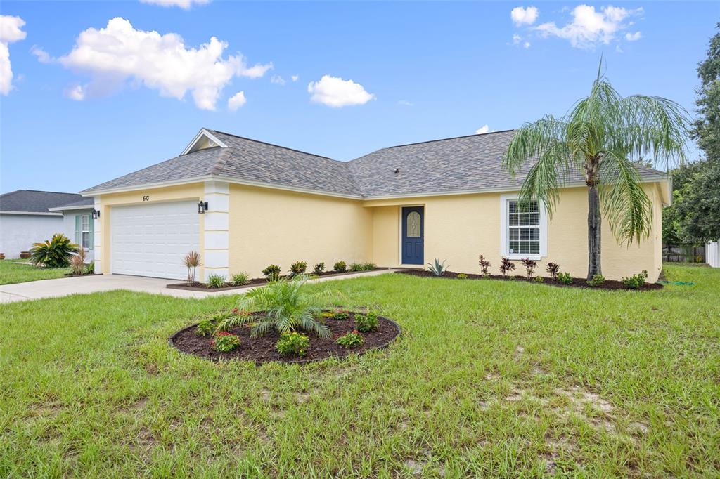A yellow single-story house with a white garage door, dark blue front door, and palm tree — 643 LAKEMONT DR, BRANDON, FL