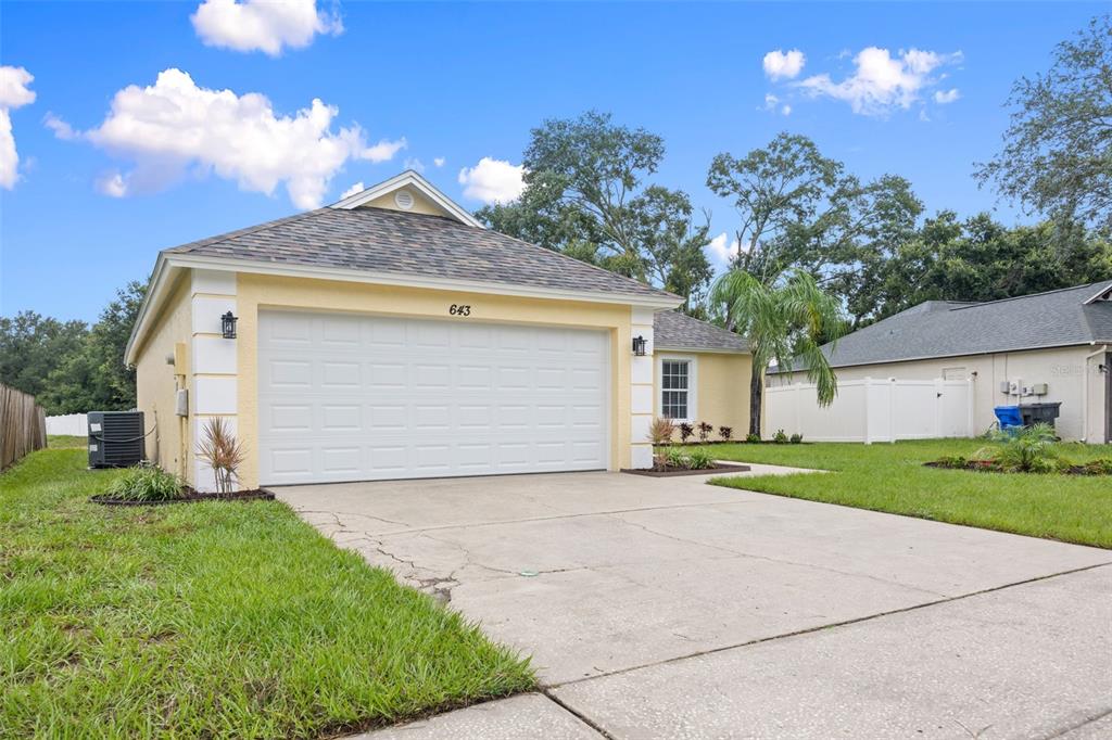 A yellow single-story house with a white garage door and a concrete driveway — 643 LAKEMONT DR, BRANDON, FL