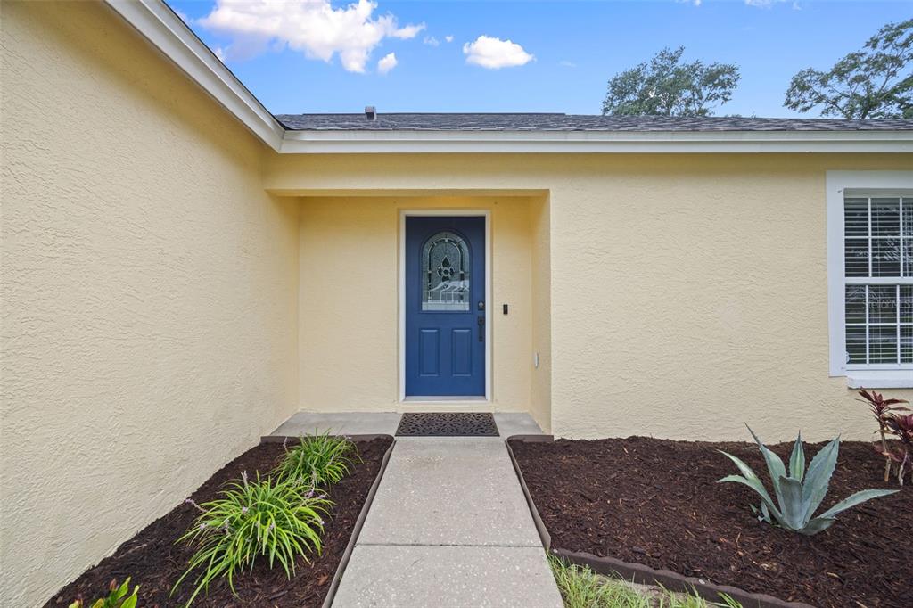 A yellow house exterior features a blue front door and a concrete walkway — 643 LAKEMONT DR, BRANDON, FL
