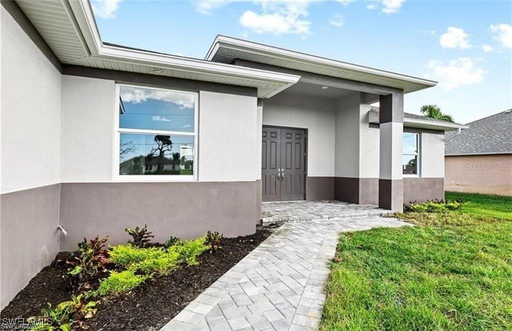 A paved walkway leads to the front entrance of a house with a two-tone exterior — 925 NW 9TH AVENUE, CAPE CORAL, FL
