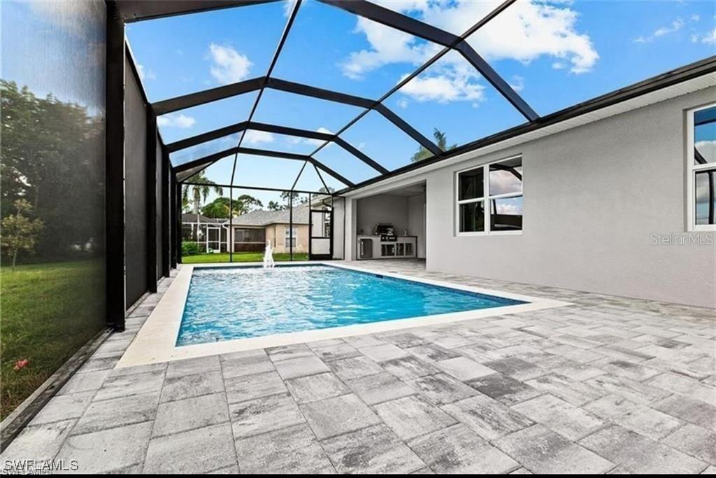 A swimming pool with a fountain is enclosed by a screened lanai with paver flooring — 925 NW 9TH AVENUE, CAPE CORAL, FL