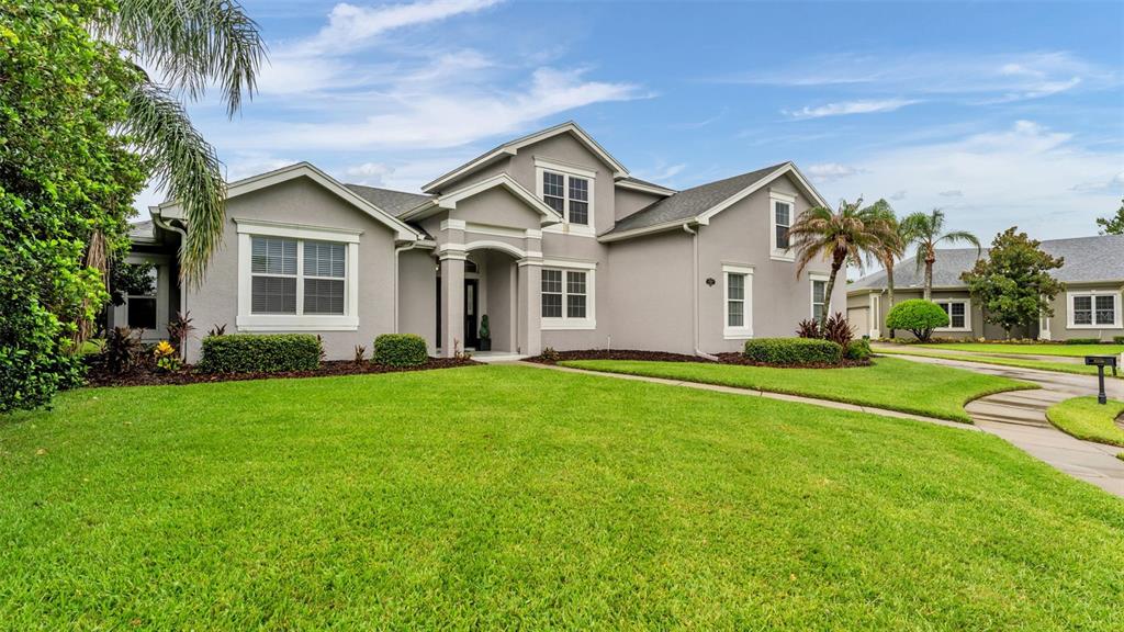 A gray two-story suburban house with a manicured lawn and a concrete driveway — 7350 OSPREY LANDING POINT, LAKELAND, FL