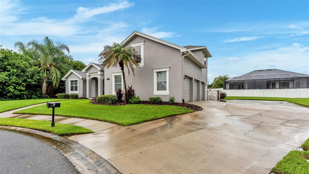 A two-story gray house features a three-car garage, a palm tree, and a concrete driveway — 7350 OSPREY LANDING POINT, LAKELAND, FL