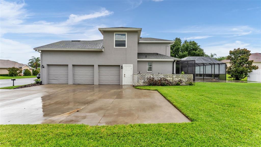 The exterior of a two-story house features a three-car garage and a screened-in pool area — 7350 OSPREY LANDING POINT, LAKELAND, FL