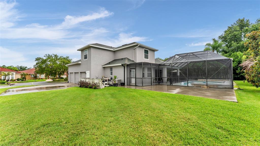 The exterior of a two-story house features a screened-in pool enclosure and a large lawn — 7350 OSPREY LANDING POINT, LAKELAND, FL