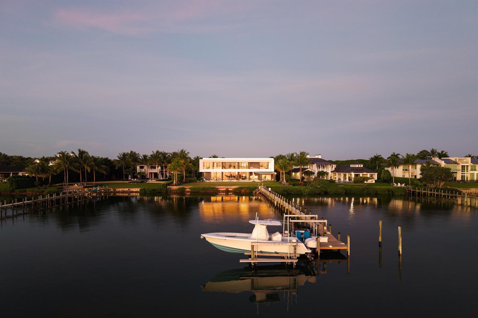 An aerial view of a modern waterfront home with a boat docked on a pier — 5211 Pennock Point Road, Jupiter FL 33458, JUPITER, FL