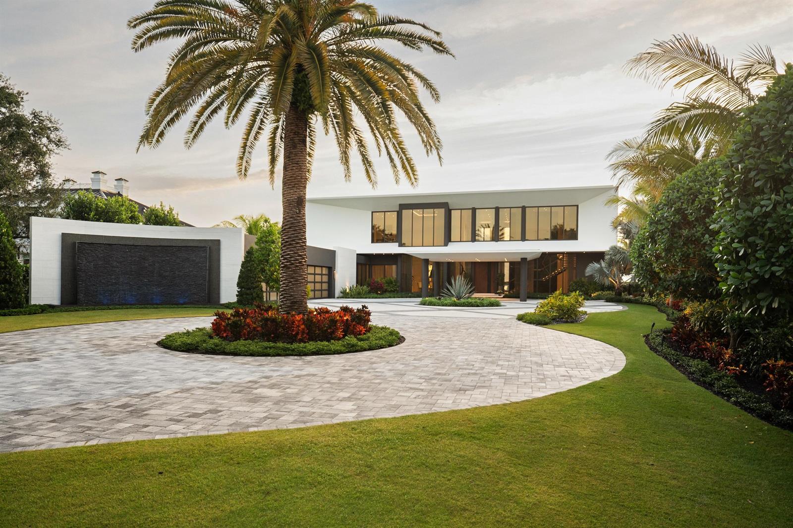 A modern two-story house features a large circular driveway, a palm tree, and a water feature — 5211 Pennock Point Road, Jupiter FL 33458, JUPITER, FL