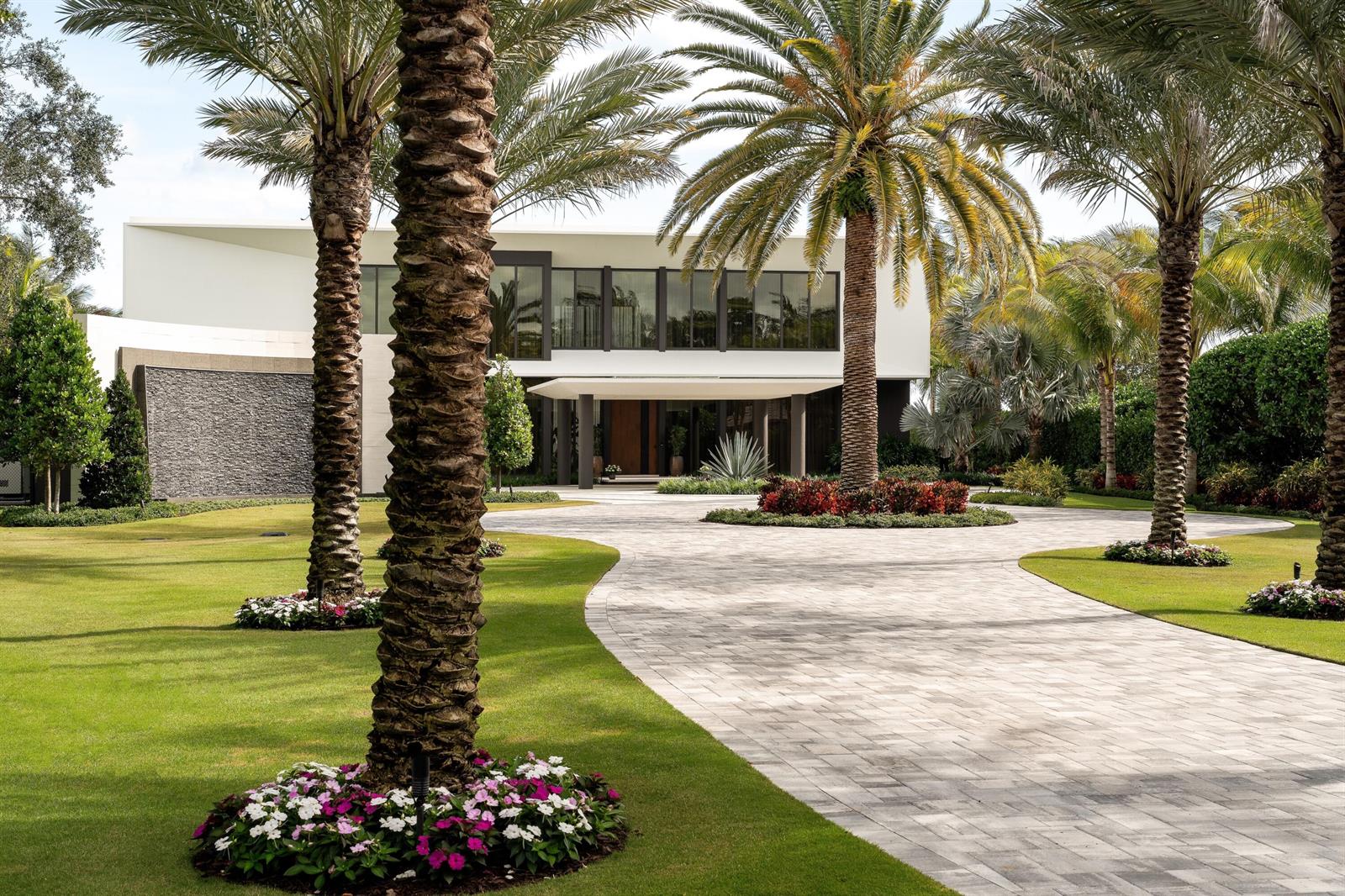 A modern two-story house with a stone water feature and palm trees along a driveway — 5211 Pennock Point Road, Jupiter FL 33458, JUPITER, FL
