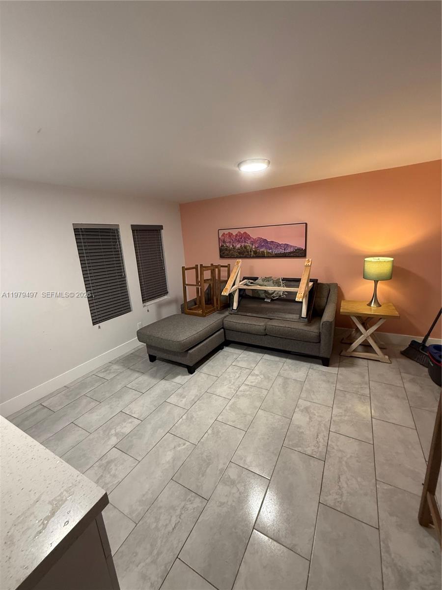 A living room features gray tile flooring, a sectional sofa, and a peach-colored accent wall — 2020 Washington St # 4, Hollywood FL 33020, HOLLYWOOD, FL