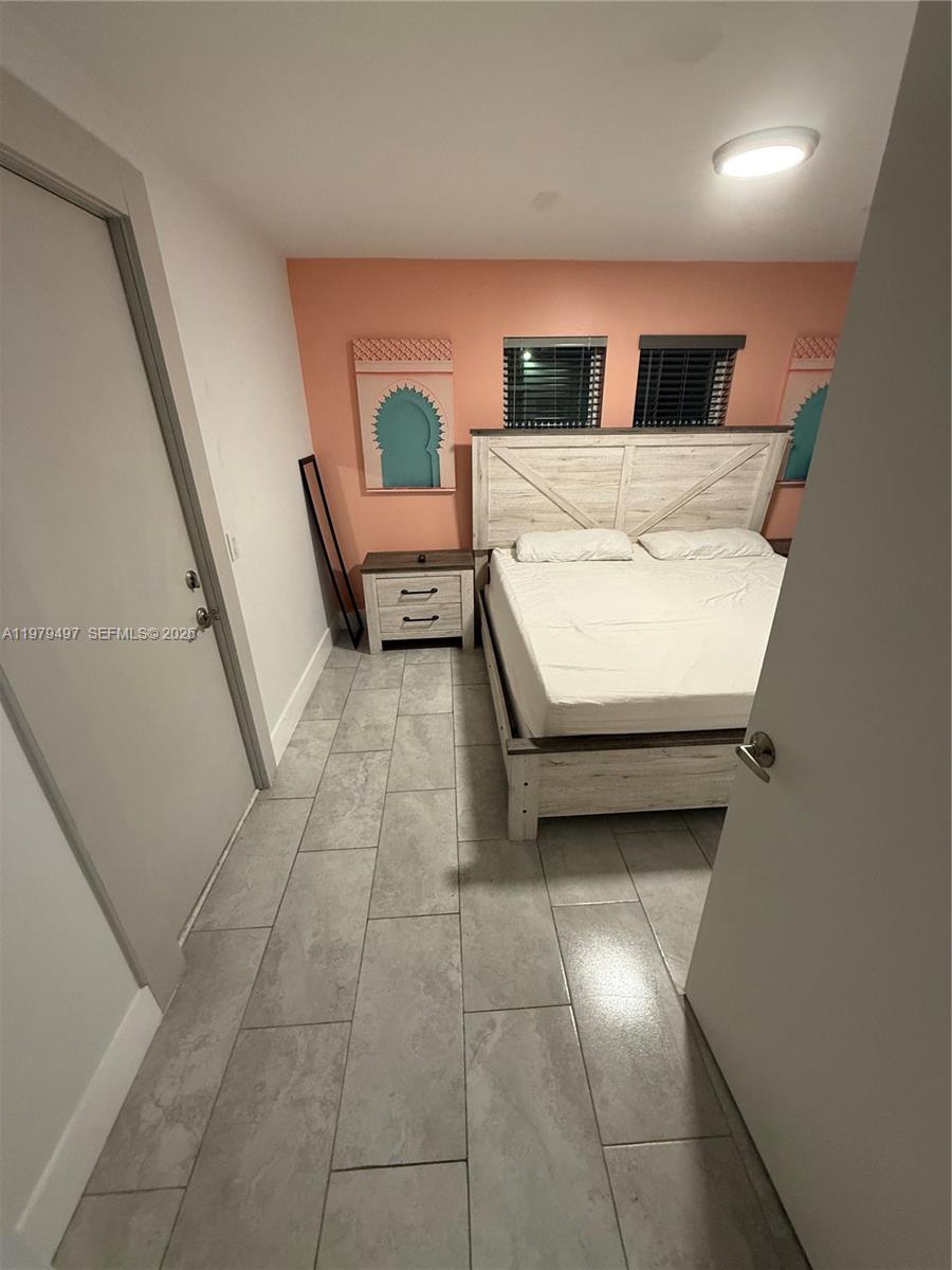 A bedroom features a white wooden bed frame, tile flooring, and a peach-colored accent wall — 2020 Washington St # 4, Hollywood FL 33020, HOLLYWOOD, FL