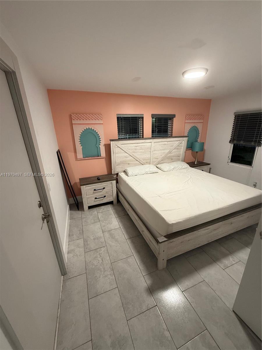 A bedroom features a white wooden bed frame, tiled floors, and a peach-colored accent wall — 2020 Washington St # 4, Hollywood FL 33020, HOLLYWOOD, FL