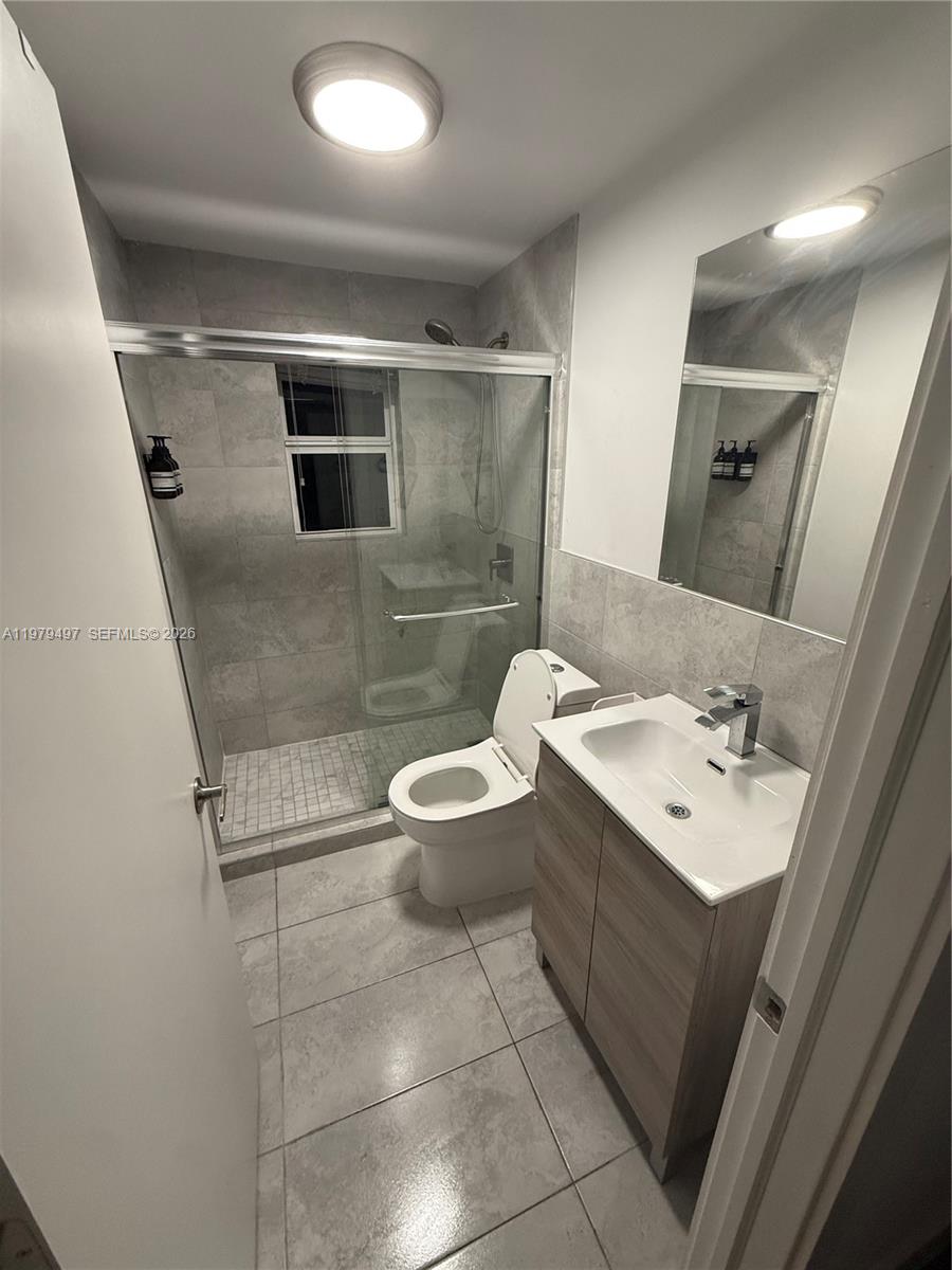 A modern bathroom features a glass-enclosed shower, a vanity with a sink, and tiled flooring — 2020 Washington St # 4, Hollywood FL 33020, HOLLYWOOD, FL