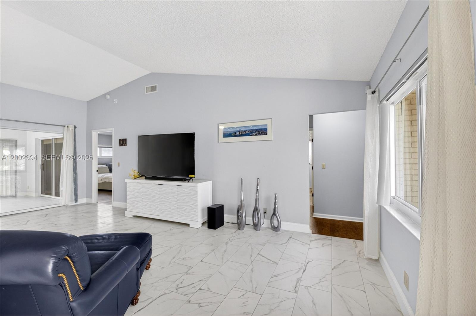 A living room features light gray walls, white tile flooring, and a vaulted ceiling — 10982 S Greentrail Dr S, Boynton Beach FL 33436, BOYNTON BEACH, FL