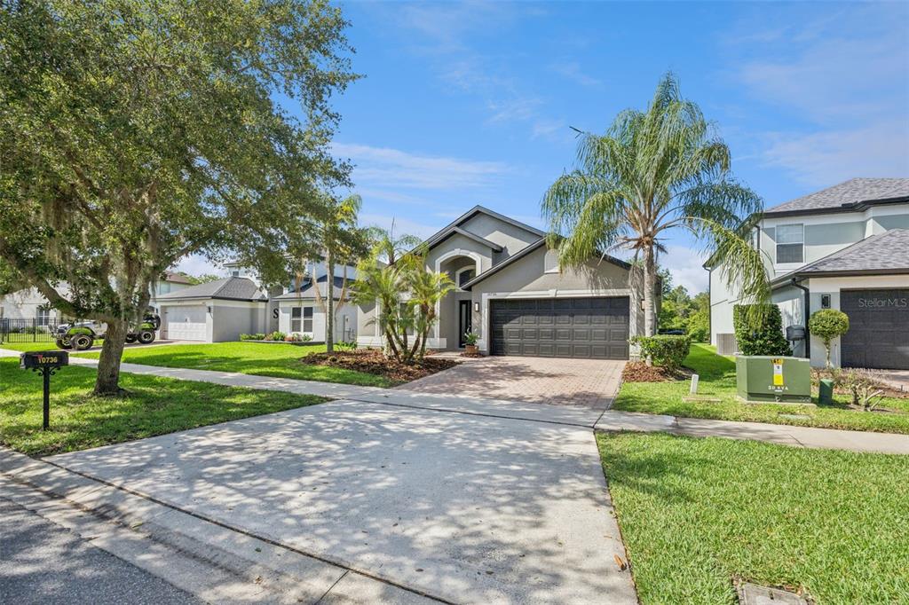 A single-story house with a gray exterior, a brick driveway, and a two-car garage — 10736 MERE PARKWAY, ORLANDO, FL