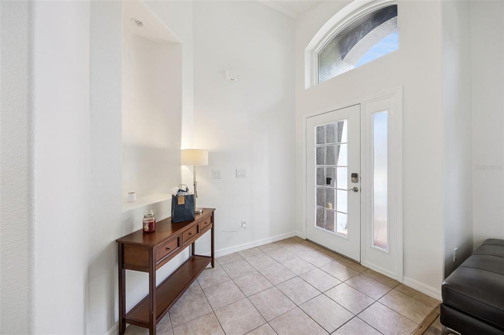 A front entryway with a black glass-paneled door, a sidelight, and a brick paver porch — 10736 MERE PARKWAY, ORLANDO, FL