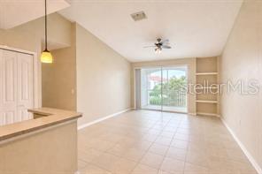 A living room with tile floors, a ceiling fan, built-in shelves, and a sliding glass door — 2549 MAITLAND CROSSING WAY UNIT 306, ORLANDO, FL