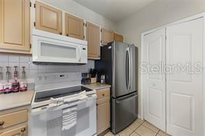 A kitchen features light wood cabinets, a white stove, a microwave, and a stainless refrigerator — 2549 MAITLAND CROSSING WAY UNIT 306, ORLANDO, FL