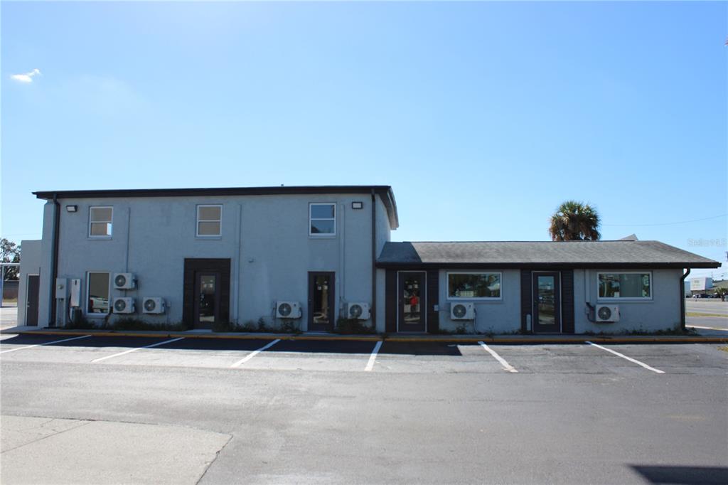 A two-story commercial building with a parking lot in front under a clear blue sky — 1516-1518 US HIGHWAY 19 UNIT D, E, HOLIDAY, FL