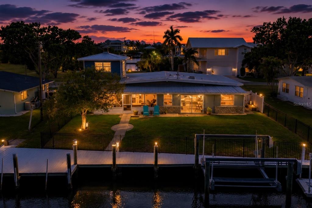 An aerial view of a waterfront house at sunset with a dock and lawn — 512 PALM AVENUE, ELLENTON, FL